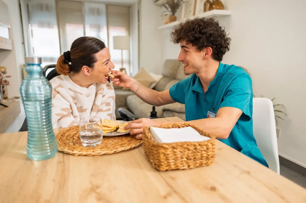 Nurse helping disabled woman eat lunch